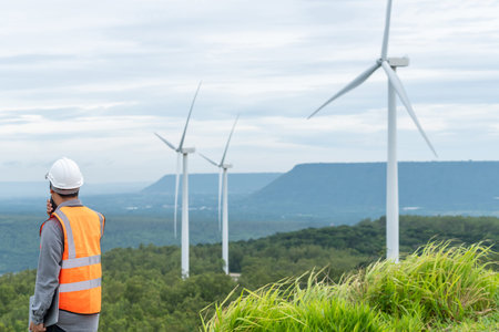 Engineer working on a wind farm atop a hill or mountain in the rural. Progressive ideal for the...