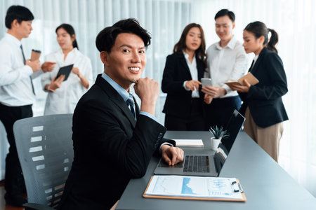 Portrait of focus young successful confident male manager, executive wearing business wear in harmony office arm crossed with blurred meeting background of colleagues, office worker.の写真素材
