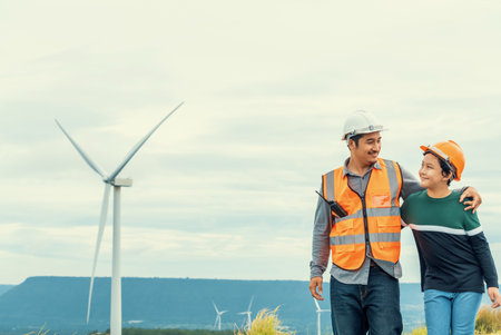 Engineer with his son on a wind farm atop a hill or mountain in the rural. Progressive ideal for the future production of renewable, sustainable energy. Energy generation from wind turbine.の写真素材