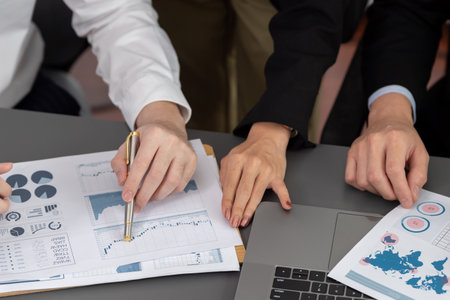 Closeup on BI dashboard on meeting desk with businesspeople analyzing or planning business strategy with hands pointing on financial paper reports as concept of harmony in office workplace.の写真素材