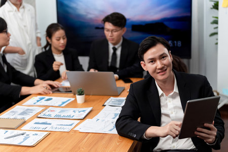 Focus portrait of successful confident male manager or executive in business wear with blurred background of businesspeople, colleagues working with financial report papers in office of harmony.の写真素材
