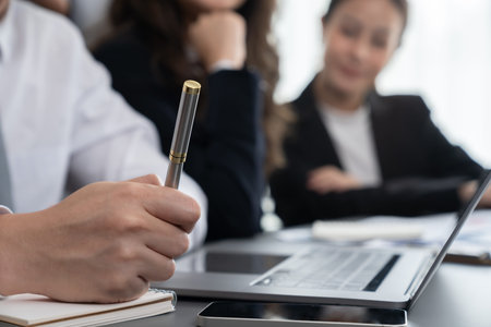 Closeup focus hand holding a pen writing, planning business strategy based on financial report from...