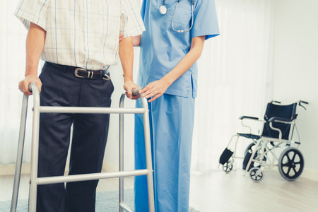 Physiotherapist assists her contented senior patient on folding walker. Recuperation for elderly, seniors care, nursing home.の写真素材
