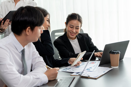 Harmony in office concept as business people analyzing dashboard paper together in workplace. Young colleagues give ideas at manager desk for discussion or strategy planning about project.の写真素材