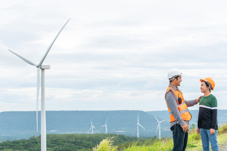 Engineer with his son on a wind farm atop a hill or mountain in the rural. Progressive ideal for the future production of renewable, sustainable energy. Energy generation from wind turbine.の写真素材