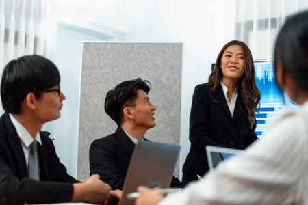 Confidence and young asian businesswoman give presentation on financial business strategy in dashboard report display on screen to colleagues in conference room meeting as harmony in workplace conceptの写真素材