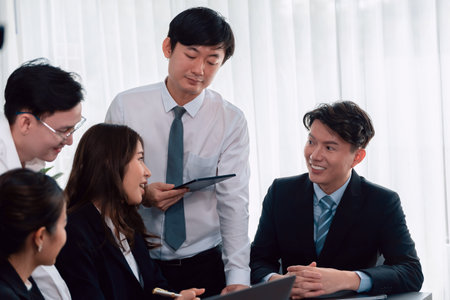 Harmony in office concept as business people analyzing dashboard paper together in workplace. Young colleagues give ideas at manager desk for discussion or strategy planning about project.の写真素材