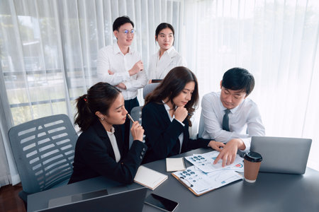 Harmony in office concept as business people analyzing dashboard paper together in workplace. Young colleagues give ideas at manager desk for discussion or strategy planning about project.の写真素材