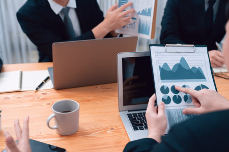 Closeup on BI dashboard on meeting desk with businesspeople analyzing or planning business strategy with hands pointing on financial paper reports as concept of harmony in office workplace.の写真素材