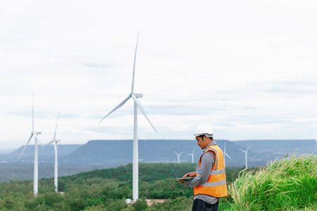 Engineer working on a wind farm atop a hill or mountain in the rural. Progressive ideal for the future production of renewable, sustainable energy. Energy generation from wind turbine.の写真素材