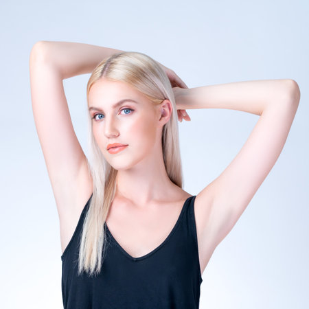 Personable woman lifting her armpit showing hairless hygiene underarm as beauty posing for cleanliness and perfect smooth skincare treatment in isolated background. Hair removal and epilation concept.の写真素材
