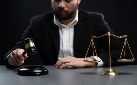 Focus symbols of justice, gavel hammer and scale balance on blurred background of thoughtful lawyer or judge sitting at his desk for integrity and fairness of the legal system. equilityの写真素材