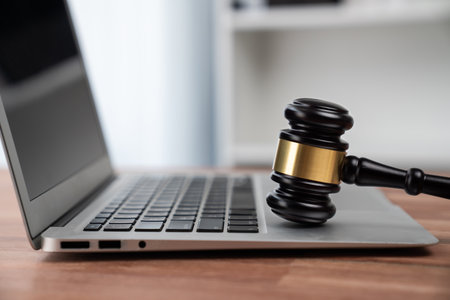 Closeup black wooden gavel hammer with laptop on desk in law firm or lawyer office background as justice and legal system for lawyer and judge, Symbolize authority and fairness in trials. equilityの写真素材