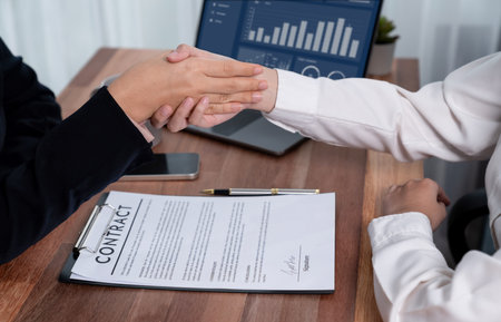 Two professionals successfully close business deal with closeup handshake, sealing the partnership agreement. Legal document and signature as formal agreement between the two companies. Enthusiasticの写真素材