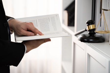 Lawyer or attorney preparing for lawsuit or litigation, reading or studying legal book at bookshelf...