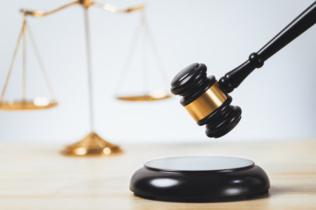 Symbolizing justice and legal authority, golden balanced scale and gavel on desk with law book in lawyer office background, reflecting concept of equality and fair judgment. equilityの写真素材