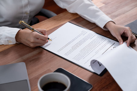 Closeup hand signing contract document with pen, sealing business deal with signature. Businesspeople finalizing business agreement by writing down signature on contract paper. Enthusiasticの写真素材