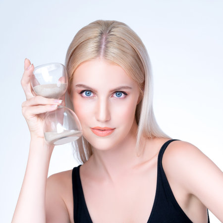 Personable model hold hourglass in aging young beauty concept of anti-aging skincare treatment for...