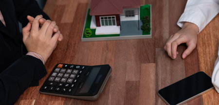 Reviewing house loan contract with agent. Analyzing financial documents and tax rates with calculator for ownership of property. Key signature for new home purchase and financing. Enthusiasticの写真素材