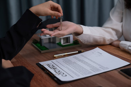 Real estate agent hands over the key to the buyer as a symbol of ownership after the successful completion of the house loan agreement, bringing the dream of a new home to life. Enthusiasticの写真素材