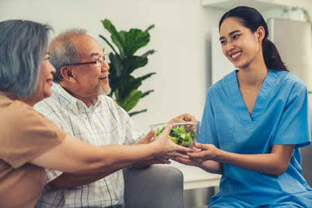 A female nurse serves a bowl of salad to a contented senior couple. Health care and medical assistance for the elderly, nursing home for pensioners.の写真素材