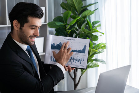 Professional businessman in black suit, present financial data or BI paper via laptop during online meeting. Remote work concept with virtual meeting presentation of effectiveness remote work. Ferventの写真素材