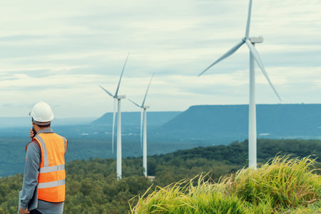 Engineer working on a wind farm atop a hill or mountain in the rural. Progressive ideal for the...