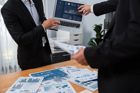 Busy analyst team discussing financial data on digital dashboard, analyzing chart and graph using data science software display on a laptop screen. Business intelligence and Fintech. Ferventの写真素材
