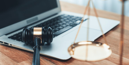 Symbolizing justice and legal authority, golden balanced scale and gavel on desk with laptop in law office background, reflecting concept of equality and fair judgment by lawyer and judge. equilityの写真素材