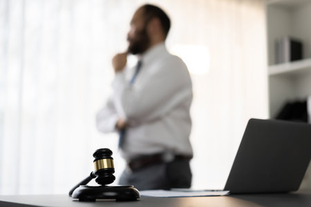 Focus wooden gavel hammer on blur background of lawyer working with legal document on desk at law firm office. Lawful hammer for righteous and equality judgment by lawmaker and attorney. Equilibriumの写真素材
