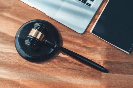 Closeup top view black wooden gavel hammer with laptop on wooden office desk or table background as justice and legal system by lawyer and judge, Symbolize authority and fairness in trial. equilityの写真素材