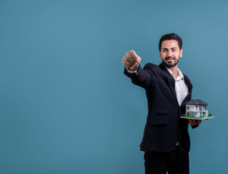 Real estate agent hold house model sample with a key on isolated background. Housing business with copyspace. Realtor presenting key property investment opportunity on house loan idea. Ferventの写真素材