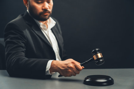Focus wooden gavel hammer with burred lawyer in black suit holding gavel in background on his desk, symbol of legal justice and integrity, balanced and ethical decision in court of law equilityの写真素材