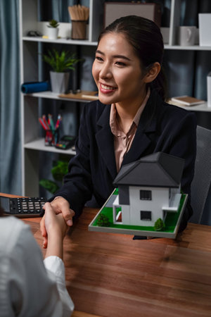 Reviewing house loan contract with agent. Analyzing financial documents and tax rates with calculator for ownership of property. Key signature for new home purchase and financing. Enthusiasticの写真素材