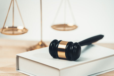 Symbolizing justice and legal authority, golden balanced scale and gavel on desk with law book in lawyer office background, reflecting concept of equality and fair judgment. equilityの写真素材