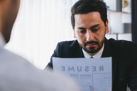 Interviewing job applicant in office with resume paper. Candidate wear suit for formal conversation with interviewer. Recruitment process with question about career and work experience. Ferventの写真素材