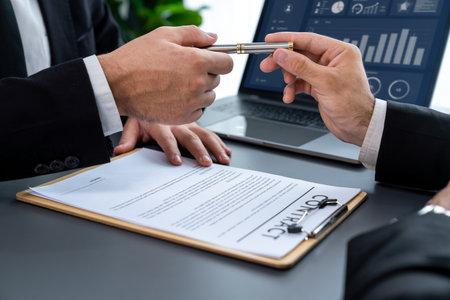 Two businesspeople sit across the desk as business deal is taking place. Corporate attorney giving a...