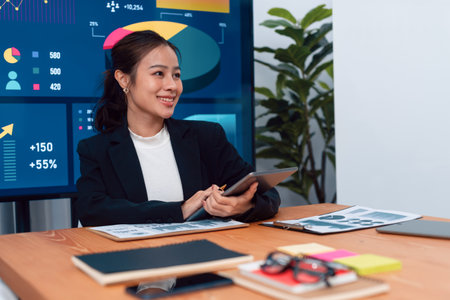 Focus portrait of female manger, businesswoman in the harmony meeting room with blurred of colleagues working together, analyzing financial paper report and dashboard data on screen in background.の写真素材