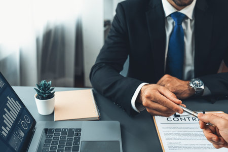Two businesspeople sit across the desk as business deal is taking place. Corporate attorney giving a pen for client or partner to sign contract paper, sealing the deal with signature. Ferventの写真素材