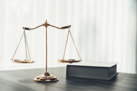 Shiny golden balanced scale and law book on desk in law school as concept justice and legal symbol. Scale balance for righteous and equality judgment by lawyer and attorney. equilityの写真素材