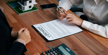 Completing the final step of the house loan process, the buyer signs the loan contract paper with a pen on the desk, securing the ownership of the property. Enthusiasticの写真素材