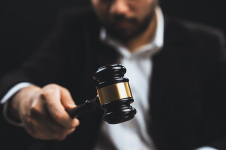 Focus wooden gavel hammer with burred lawyer in black suit holding gavel in background on his desk, symbol of legal justice and integrity, balanced and ethical decision in court of law equilityの写真素材