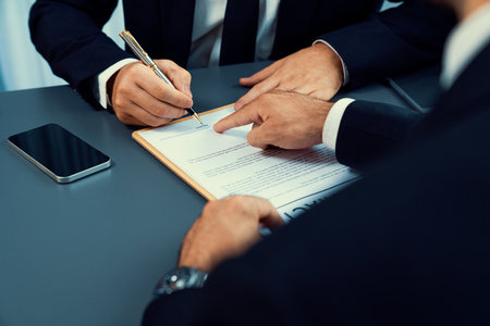 Closeup hand signing contract document with pen, sealing business deal with signature. Businesspeople finalizing business agreement by writing down signature on contract paper. Ferventの写真素材