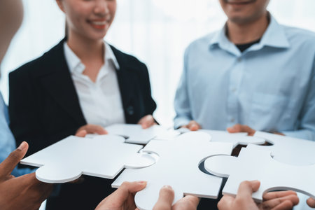 Diverse corporate officer workers collaborate in office, connecting puzzle pieces to represent partnership and teamwork. Unity and synergy in business concept by merging jigsaw puzzle. Concordの写真素材