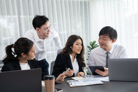 Harmony in office concept as business people analyzing dashboard paper together in workplace. Young colleagues give ideas at manager desk for discussion or strategy planning about project.の写真素材