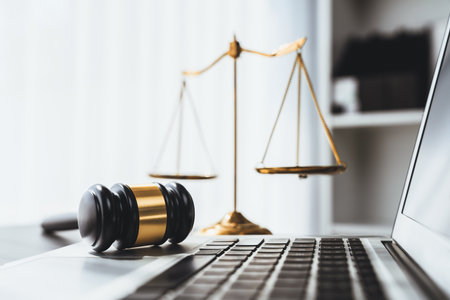 Symbolizing justice and legal authority, golden balanced scale and gavel on desk with laptop in law office background, reflecting concept of equality and fair judgment by lawyer and judge. equilityの写真素材