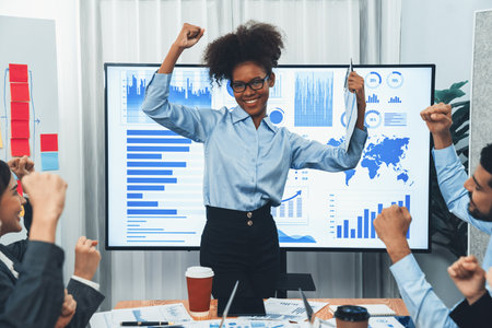 Business people celebrate after successful presentation or meeting on data analysis display on TV screen. Happy team gathers in office room, cheer to collaboration with celebratory gesture. Concordの写真素材