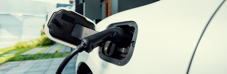 Closeup electric vehicle plugged-in with cable from charging point powered for progressive concept...