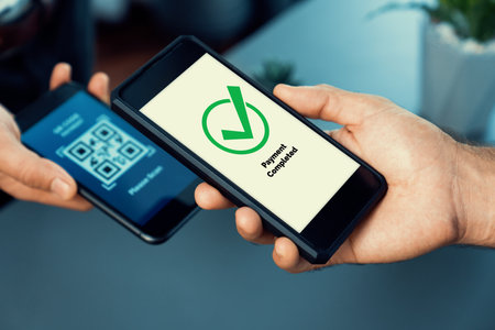 QR code displayed on screen for cashless payment scanning. Closeup hands hold smartphone to transfer...