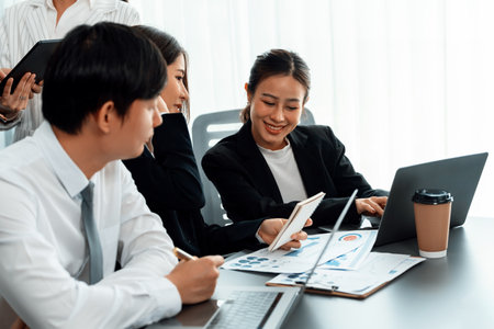 Harmony in office concept as business people analyzing dashboard paper together in workplace. Young colleagues give ideas at manager desk for discussion or strategy planning about project.の写真素材
